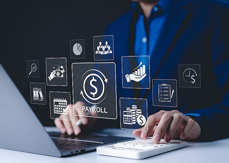 A payroll employee working on his laptop illustrated with payroll management system concept graphics.