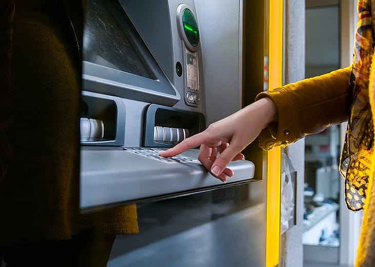 A woman entering info in an ATM to withdraw money.