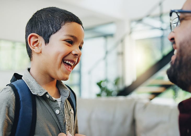 A young boy getting ready to go to school talking with his dad.
