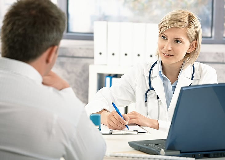 A doctor takes notes while consulting with her patient.