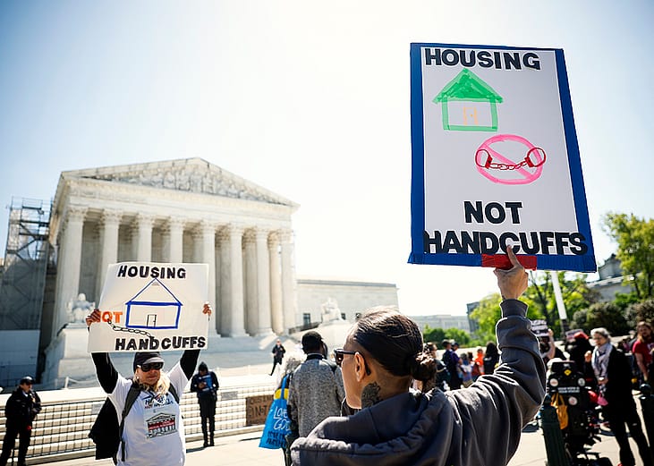 Homeless rights activists hold up signs saying "Housing, Not Handcuffs" outside of the U.S. Supreme Court on April 22, 2024 in Washington, DC.