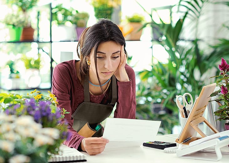 A small plants business owner worried looking at a bill.