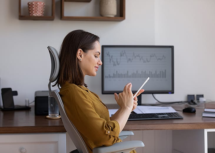A female finance trader using her smartphone at work.
