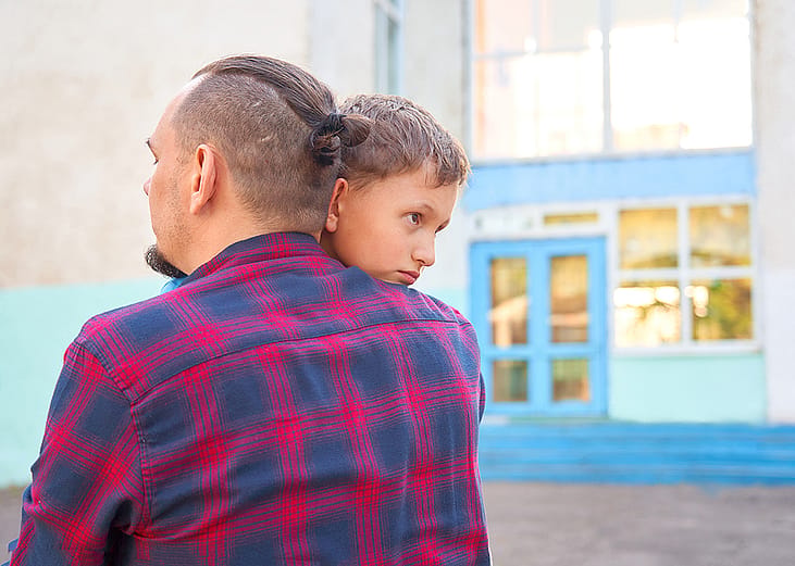 A father hugs his young son before leaving for school.