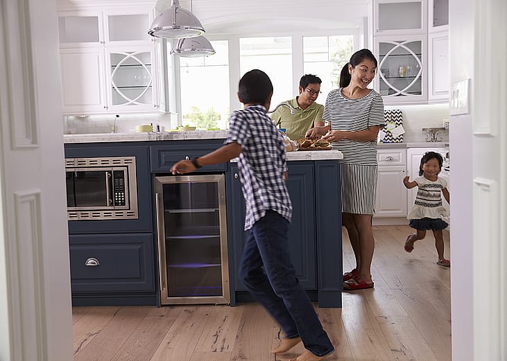 Parents prepare food as their children play around the kitchen.
