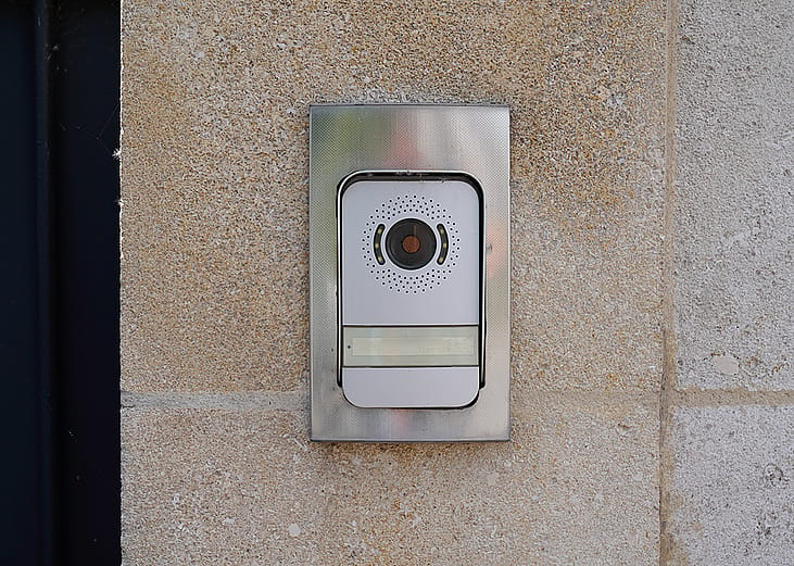 A surveillance video doorbell on a modern house's door.