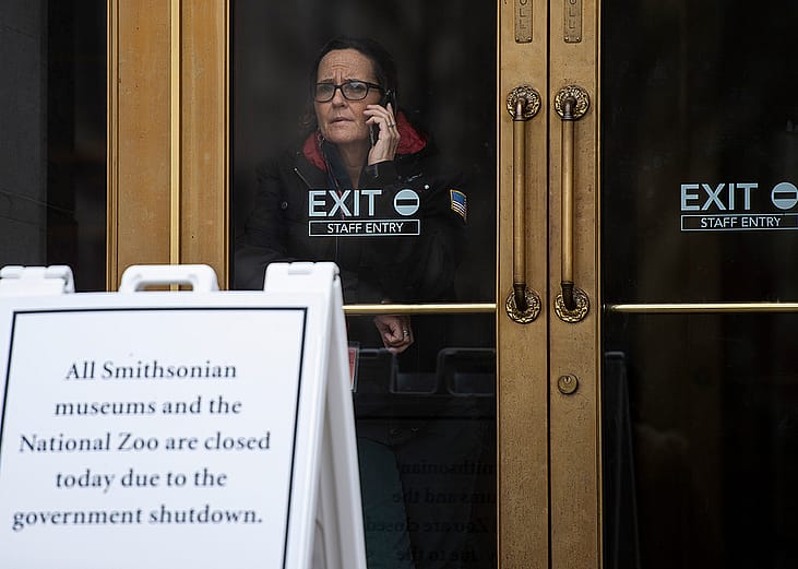 A US government employee talks on the phone as she looks out of a closed Smithsonian museum in Washington, DC on January 18, 2019, where the government has been shut down for four weeks.