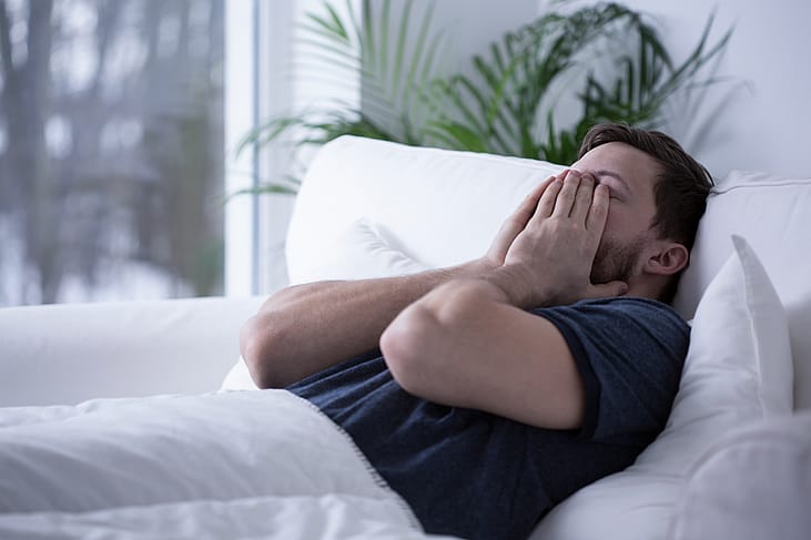 A man on bed struggling to sleep.