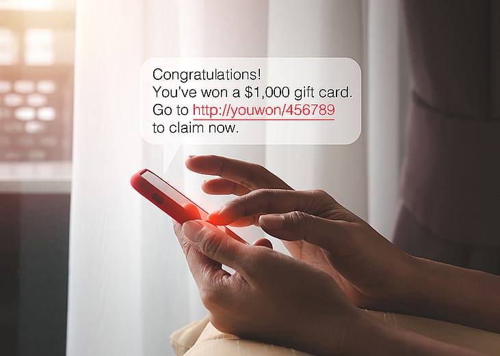 SMS chat bubble displaying a cash prize message over a person typing on a smartphone.