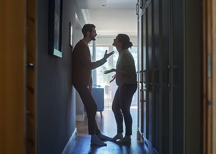 A couple fighting in a hallway of their apartment.
