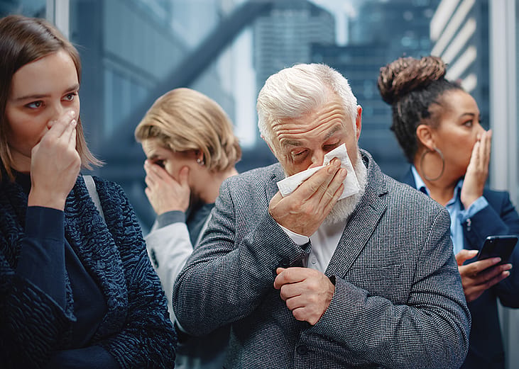 A middle-aged man sneezes in a crowded elevator.
