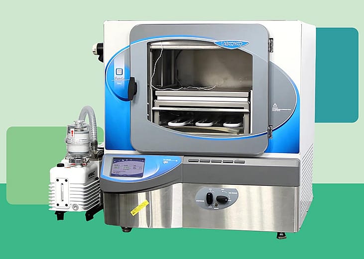Photo of modern lab freeze dryer cut out against a stylized background of different shades of green blocks. 