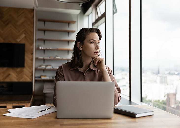 A young businesswoman in an office looking out the window.