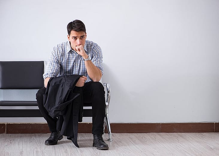 A man sits nervously waiting in a lobby.