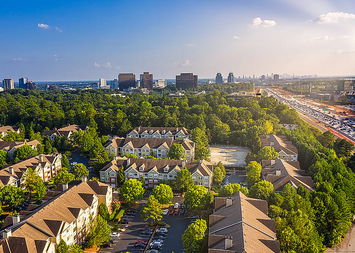 Condos in Atlanta suburbs just next to Highway GA 400 with blue sky and downtown in background.