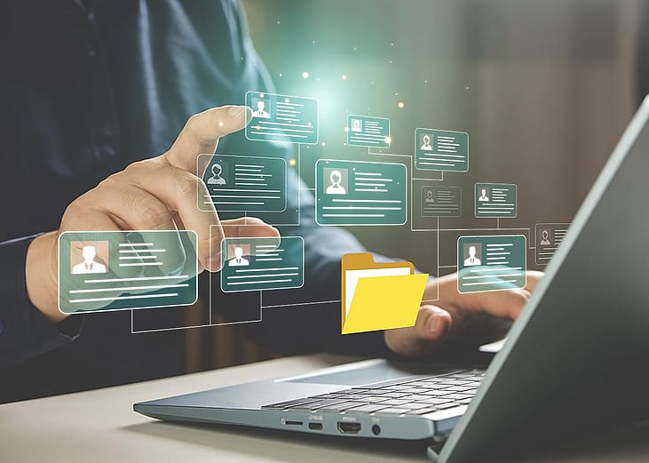 Businessperson using a laptop hovers at graphic illustration of a personal file management software.