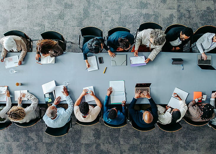 Top view of a large business group around a table during a meeting.