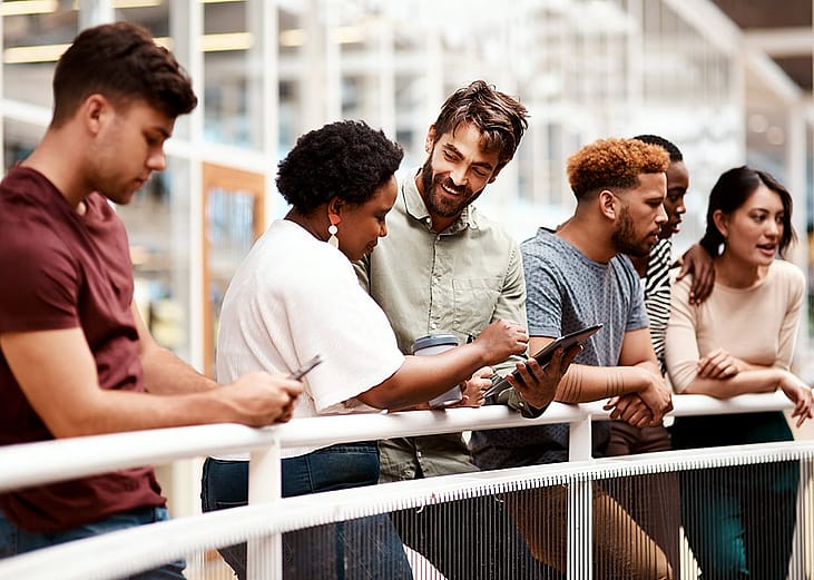 An office team engaged in discussion while standing by a railing.