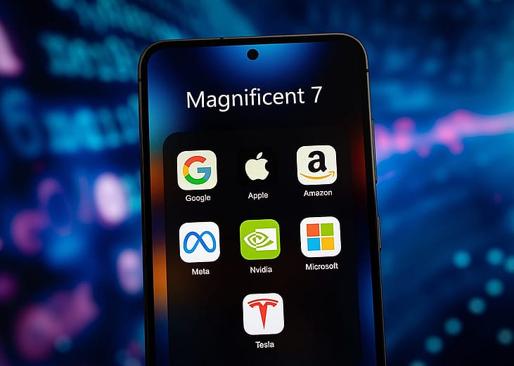 A smartphone's app folder named 'Magnificent 7' and displays app icons of Google, Apple, Amazon, Meta, Nvidia, Microsoft, and Tesla.