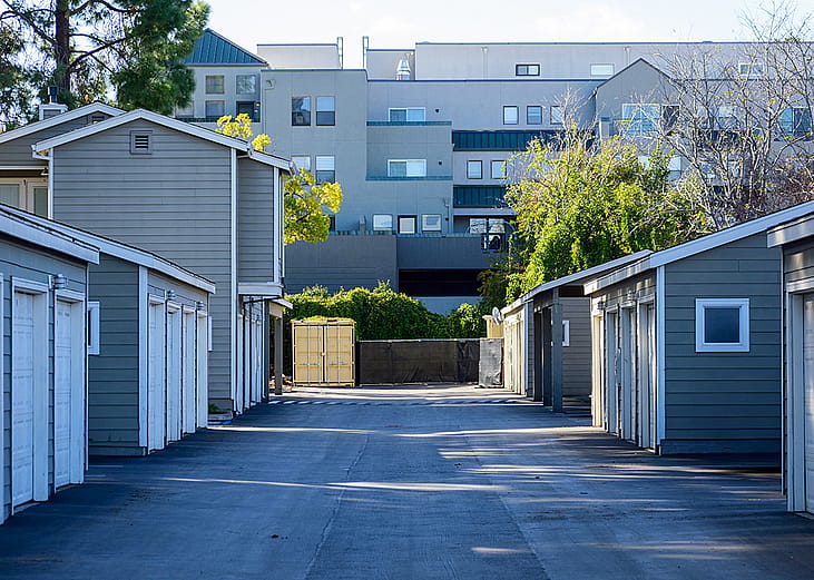 Symmetrical view of urban apartments' garages in a paved driveway.