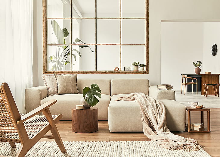 Interior of a modern living room with a modular sofa, decorated with beige and wooden motifs.