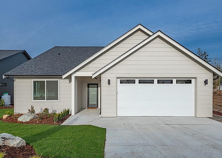 Middle class home exterior small rambler style house with simple style brand new construction blue sky green grass winter season family residence in a suburban neighborhood.