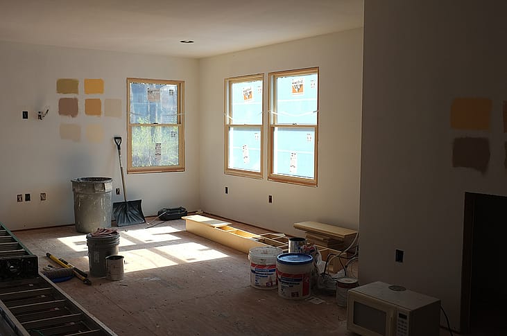 Paint samples on a wall of a sun-lit room with remodeling in progress.