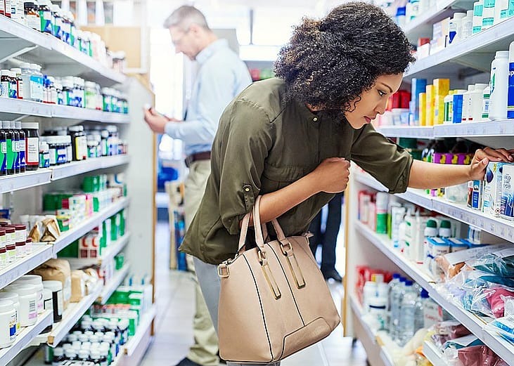 A person looking at products in the aisles of a retail drugstore.