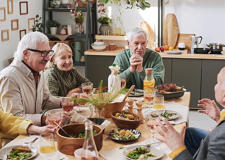 A group of senior people talking to each other at the dinner table.