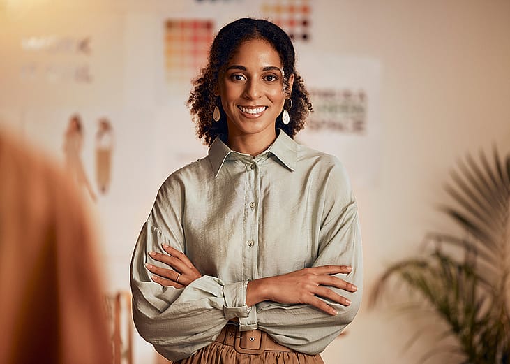 A black female fashion designer posing in her studio.