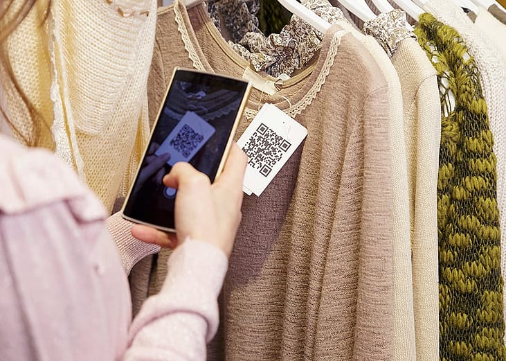 A woman scanning a clothing item's QR code on her phone.