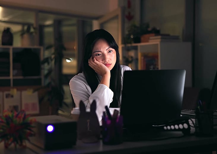 A tired female employee working overtime in the office at night.