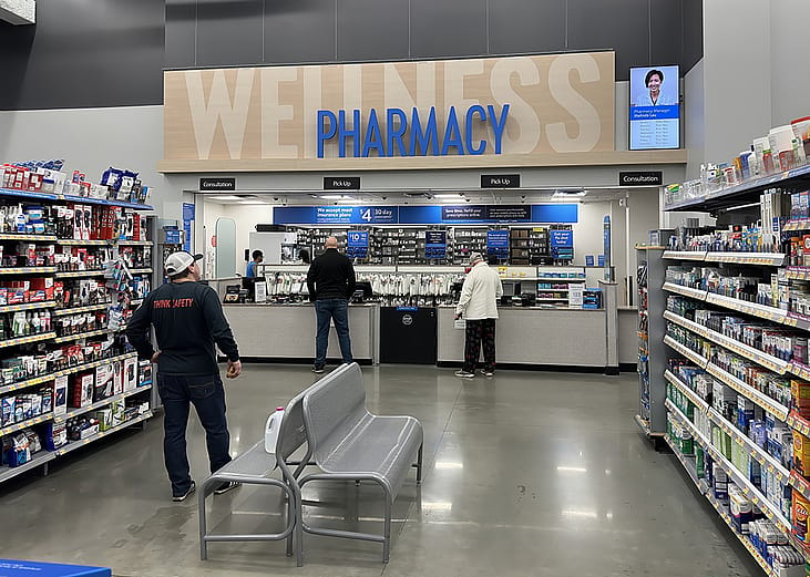 Customers picking up items at a pharmacy counter.