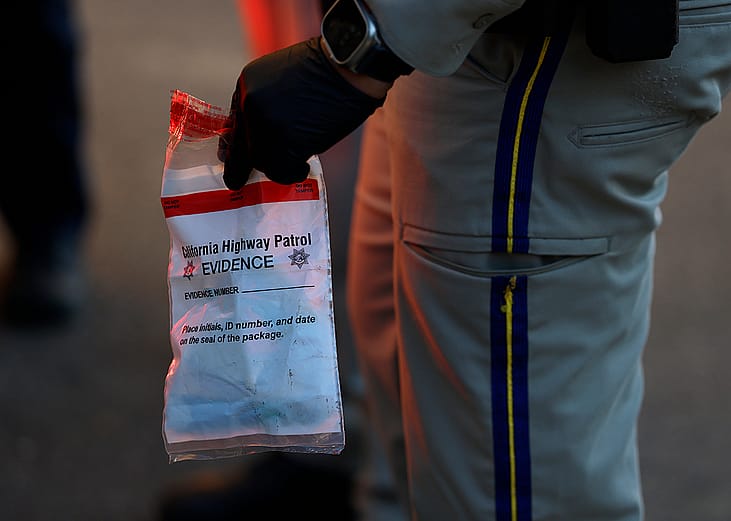 A California Highway Patrol officer holding an evidence bag after taking a suspect into custody.