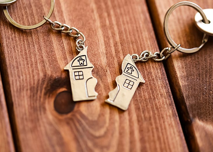 Two halves of a home keyholders as a concept of property sale after divorce.