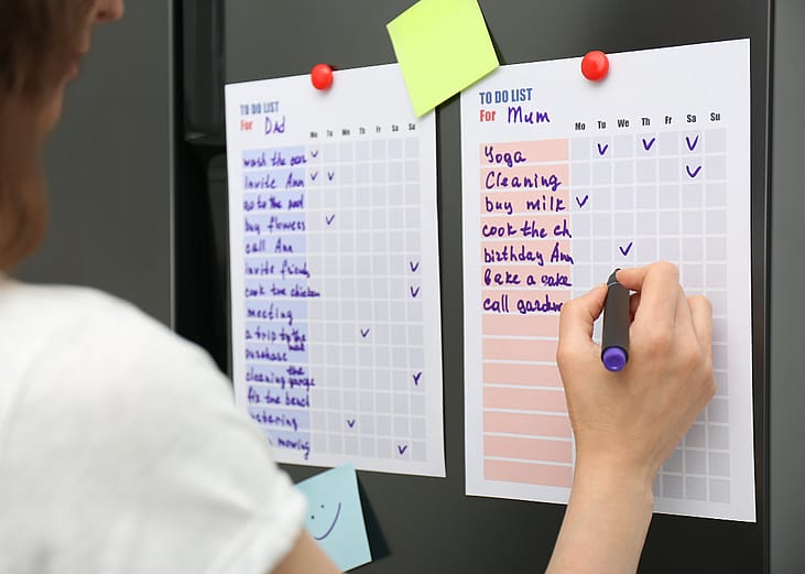 A person checking a to do list on refrigerator door.