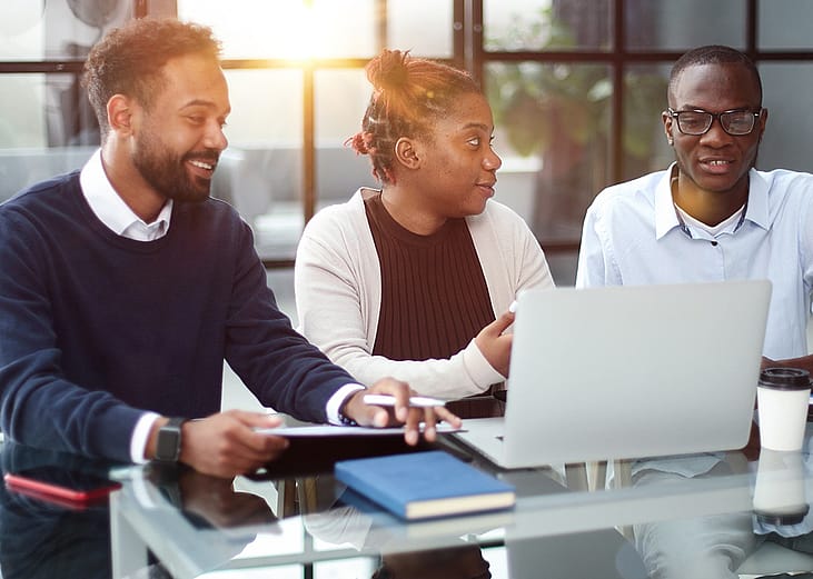 Three members of a business team brainstorming on strategy in an office.