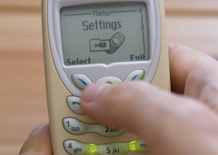 A retro Nokia 3410 mobile phone in someone's hand with the settings menu open.