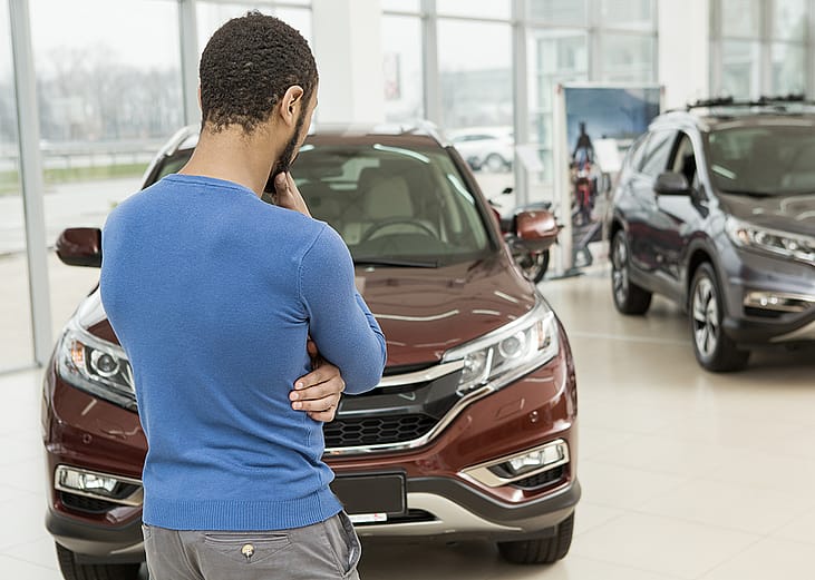 Rear view of a man choosing a car at a dealership.