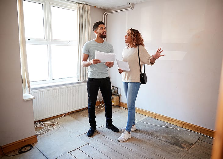 A couple surveys a house's area for renovation.