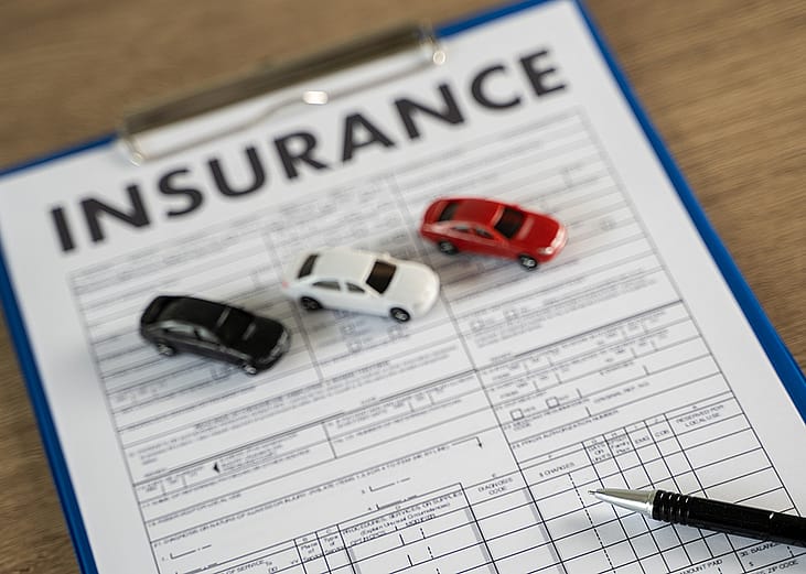 Three small figures of cars on top of a car insurance document.