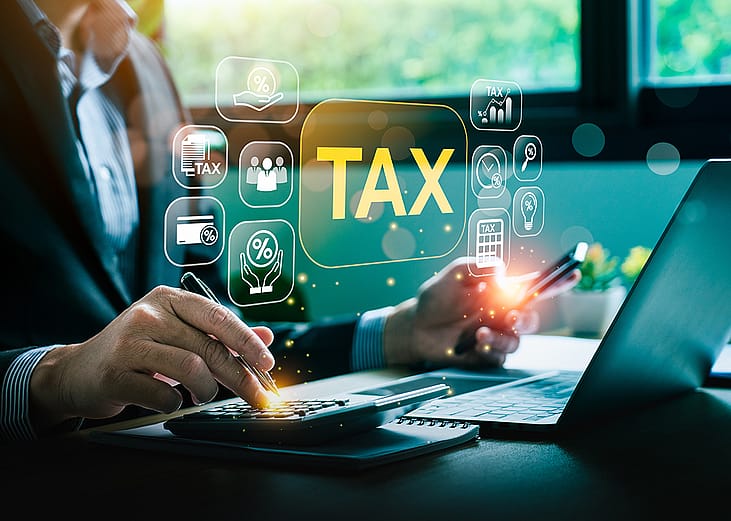 A businessman calculating taxes illustrated with tax deduction software graphics.