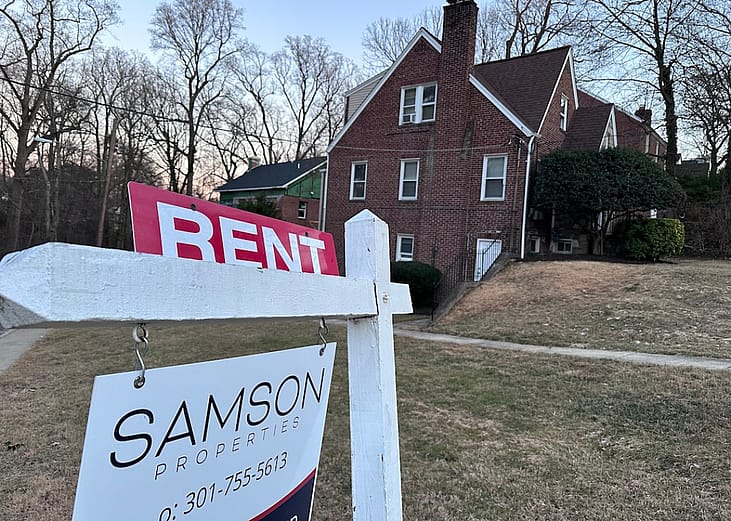 A sign in foreground lists a home for rent in Maryland with tall brick home in the background. Municipal rental registries are gaining attention as cities try to get a handle on who owns rental properties and where, both to better understand their housing landscape and to ensure rentals are safe for tenants. 