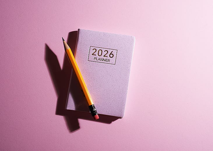 A pink 2026 planner with a pencil against a pink background.