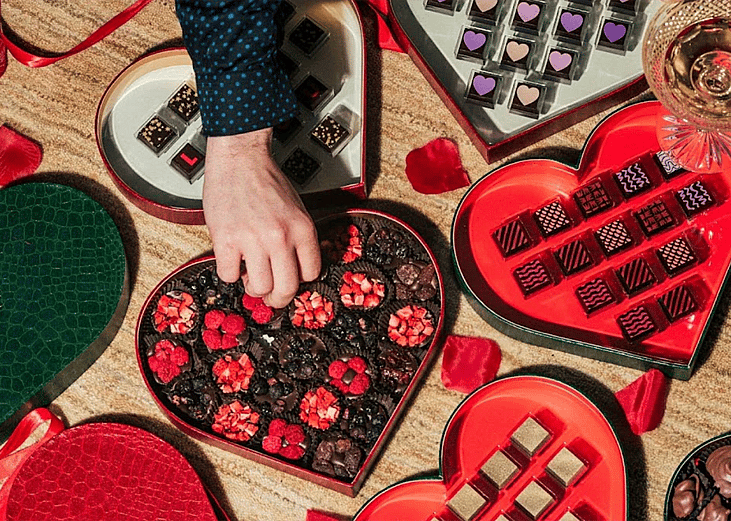 Person picking from a heart-shaped box of chocolates.