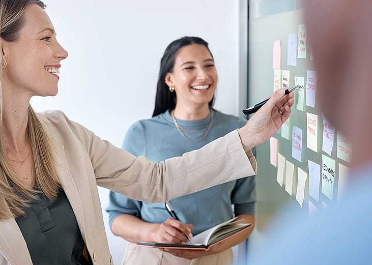 A business team planning for a project using sticky notes on a board.
