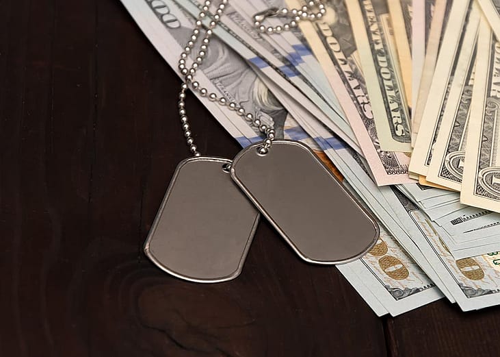 Army badges on top of banknotes as a concept of veterans debt relief.