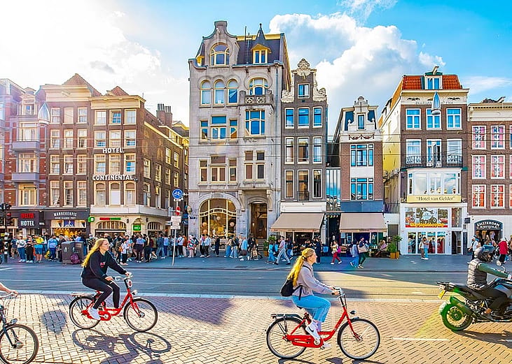 People riding bicycles along Damrak street in central Amsterdam.