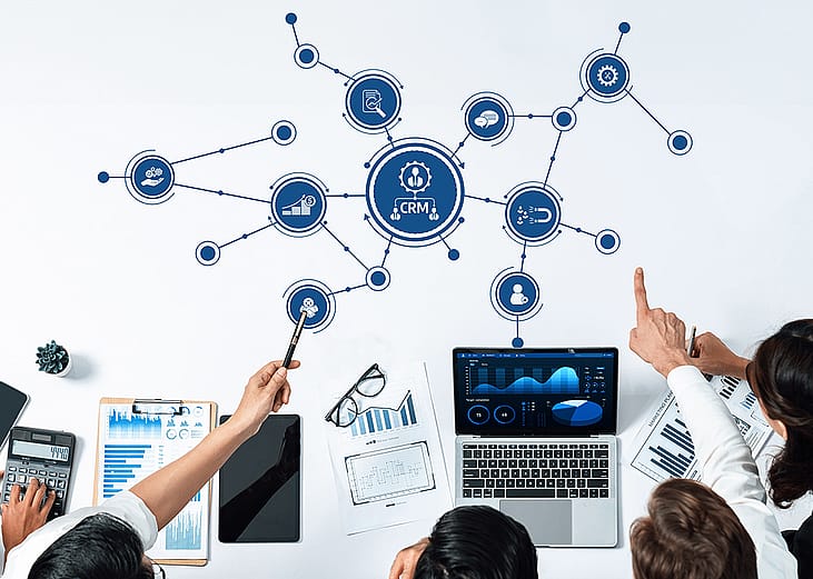 A business team collaborating and illustrated utilizing a CRM tool.