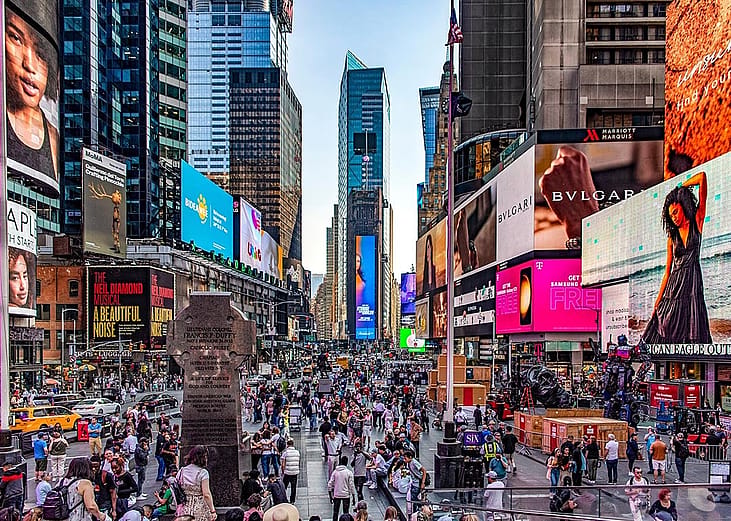 Crowds of people and lit up billboards around Times Square in New York City. 